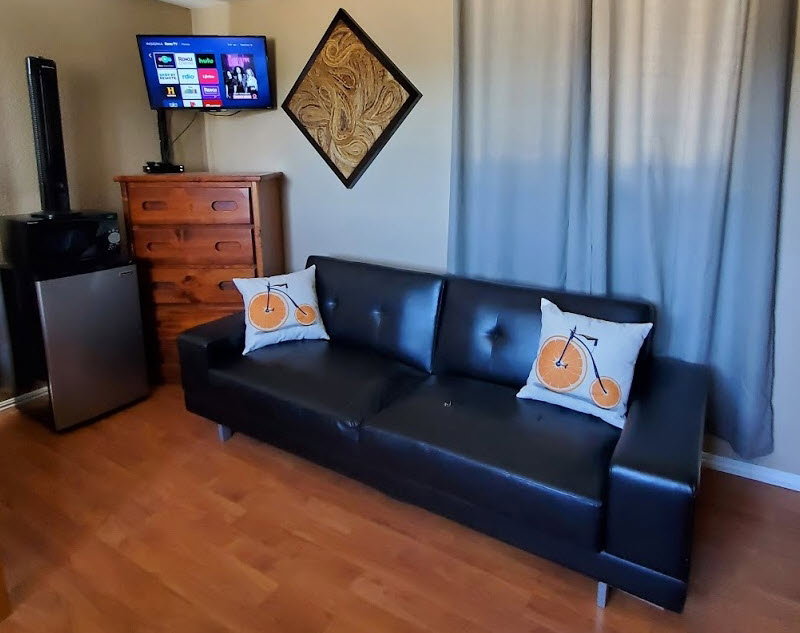 Sofa, mini fridge in room, cable TV, dresser.